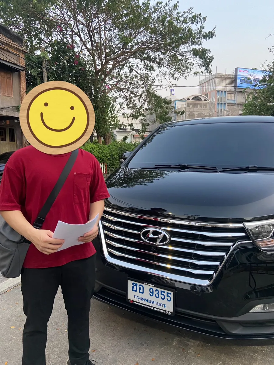 ลูกค้ายืนถ่ายรูปคู่กับรถตู้ Hyundai สีดำตอนรับรถ